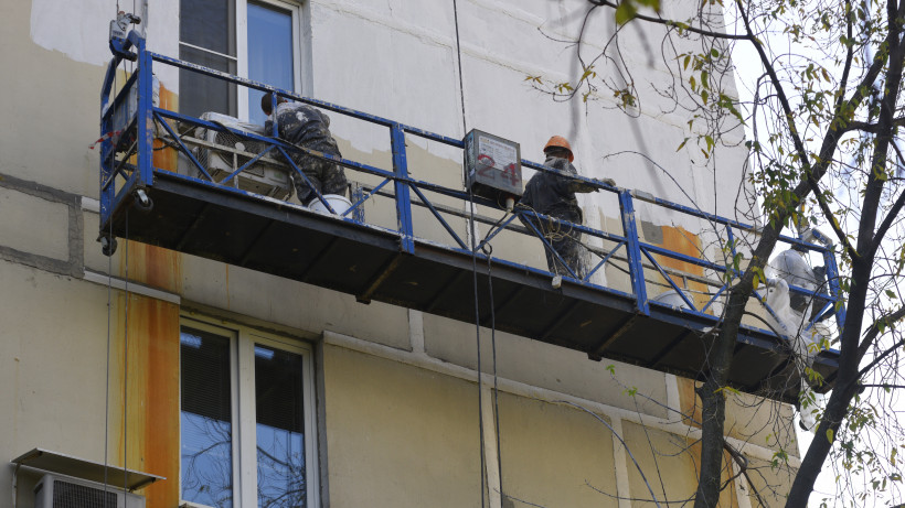 Коммунальная служба ремонтирует фасад жилого дома