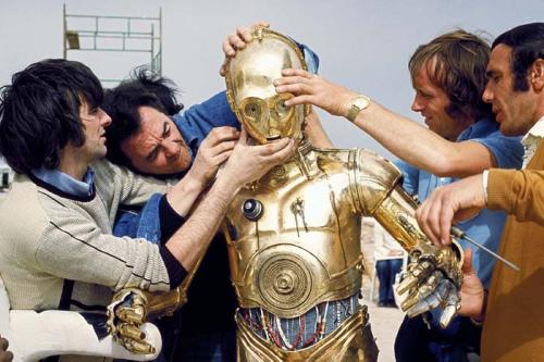 Энтони Дэниелс облачается в костюм C-3PO А для воплощения инопланетянина Чубакки проблема была противоположной – требовался гигант. Поэтому непрофессиональный актер Питер Мехью получил эту роль без проб, он просто встал с кресла, и был тут же утвержден – не часто на улицах встретить человека ростом в 221 см. Бывшего фельдшера облачили в костюм, связанный из шерсти ангорских коз, и также отправили на съемки в жаркие страны. Когда его спрашивали, каково это было, тот сравнивал свое состояние с едой в микроволновке. Кстати, голос, которым разговаривает Чубакка – это смесь криков различных животных: медведя, льва, тигра и моржа.