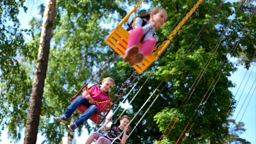 Дети катаются на карусели в летнем парке