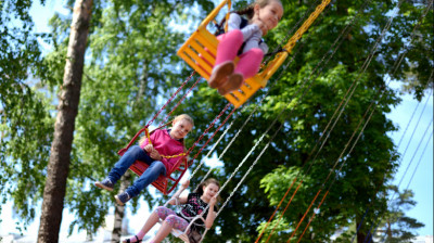 Дети катаются на карусели в летнем парке